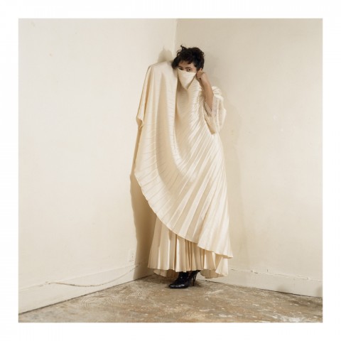 Jeune femme brune cachant son visage derrière un pan de sa robe blanche. Paris 2005